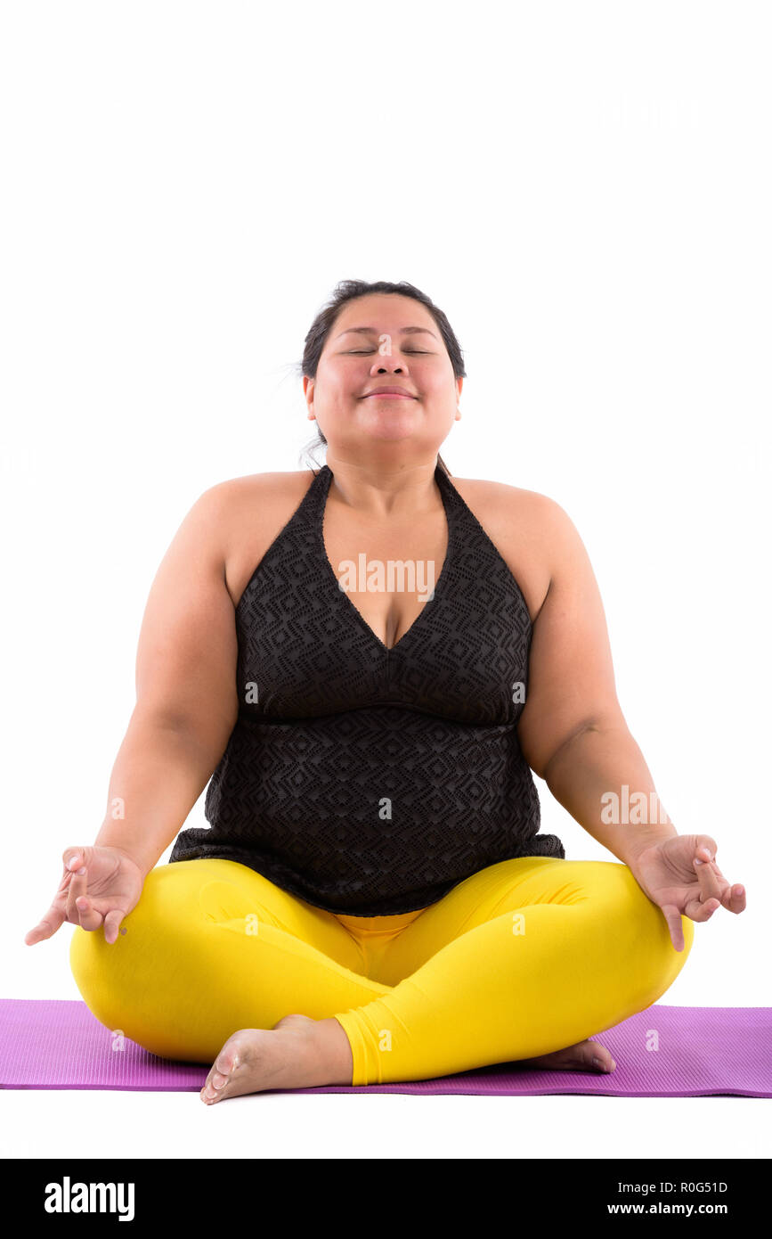 Studio shot di grasso di giovane donna asiatica meditando con gli occhi chiusi Foto Stock