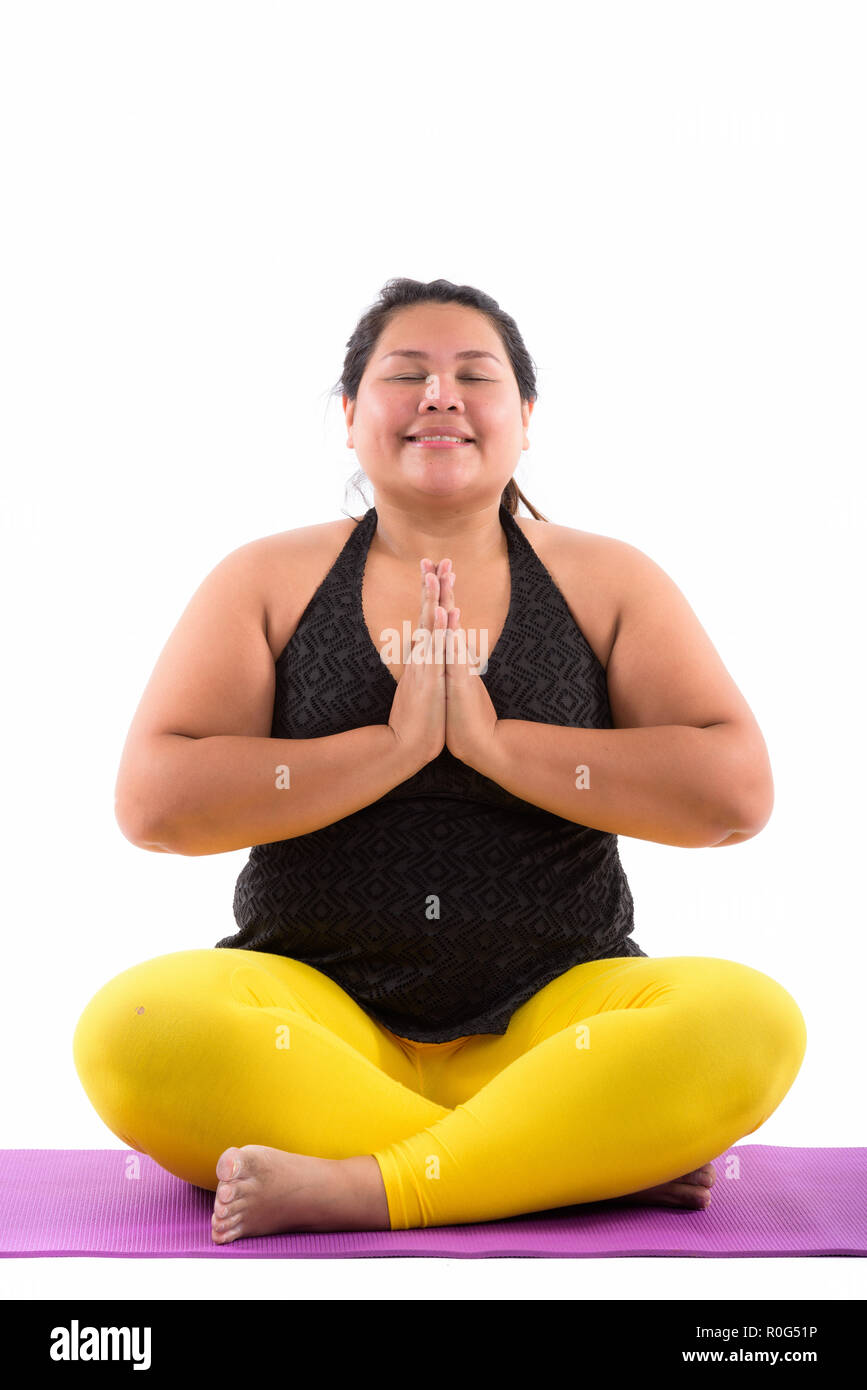 Studio shot di giovani felici fat donna asiatica sorridere mentre meditat Foto Stock