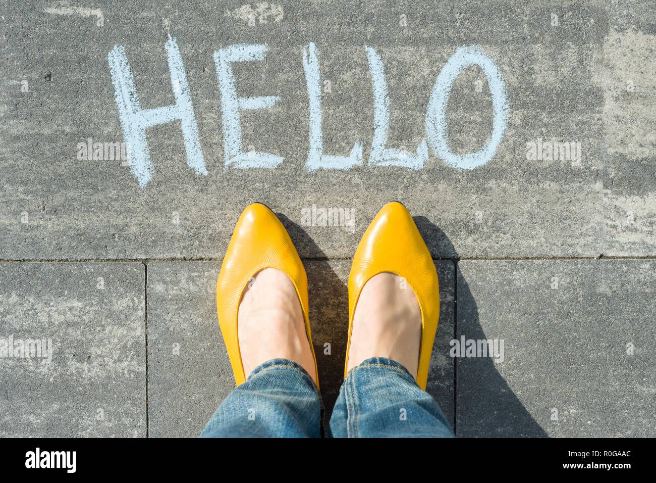 I piedi femminili con testo ciao scritto su asfalto. Foto Stock