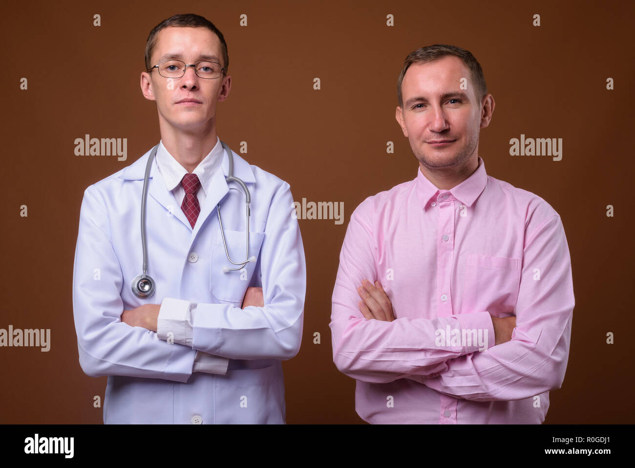 Giovane medico e paziente uomo contro lo sfondo marrone Foto Stock