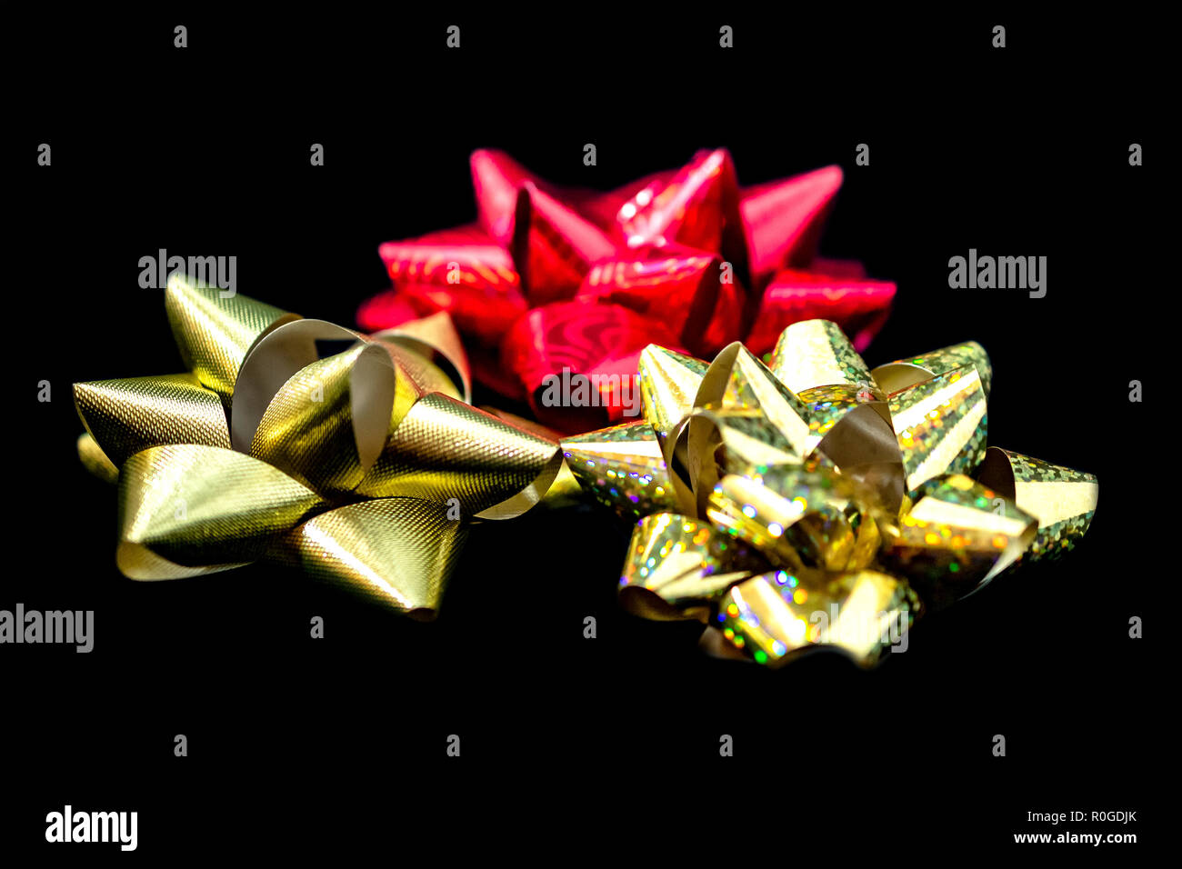 Tre (3) Natale in satin nastri - 1 oro, 1 rosso, 1 oro olografica a colori su sfondo nero. Camera per copia. Foto Stock