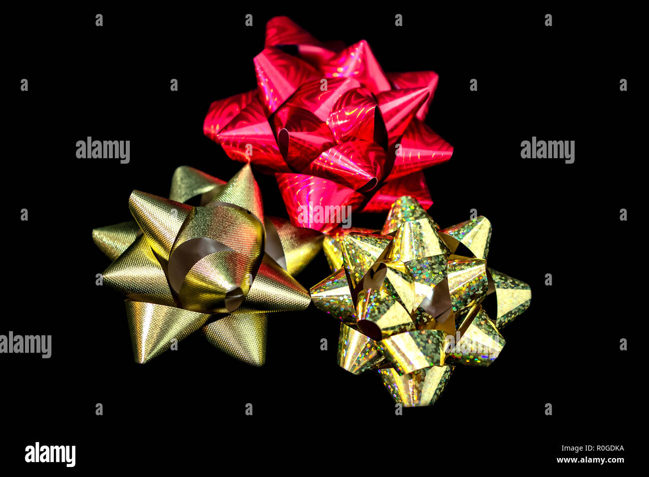 Tre (3) Natale in satin nastri 2 color oro 1 di colore rosso. Sfondo nero. Camera per copia. Foto Stock