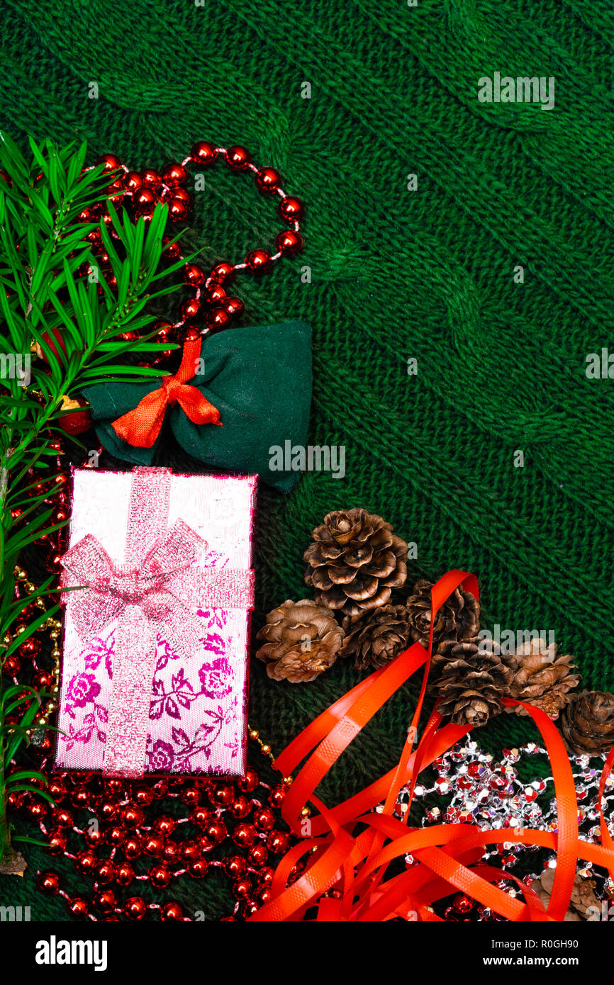 Regalo di Natale decorato con ramo verde, Pigna, borsa regalo di rosso e argento perle garlans sulla maglia blacket . Natale o Capodanno sfondo verde, Foto Stock