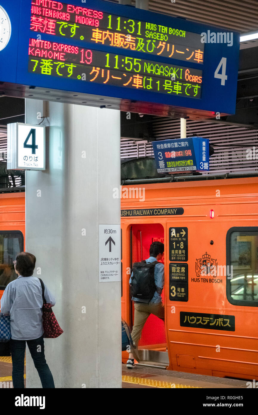 Una speciale orange JR Kyushu convoglio ferroviario di Huis ten Bosch theme park a Sasebo è in partenza da Fukuoka la Stazione di Hakata. Foto Stock