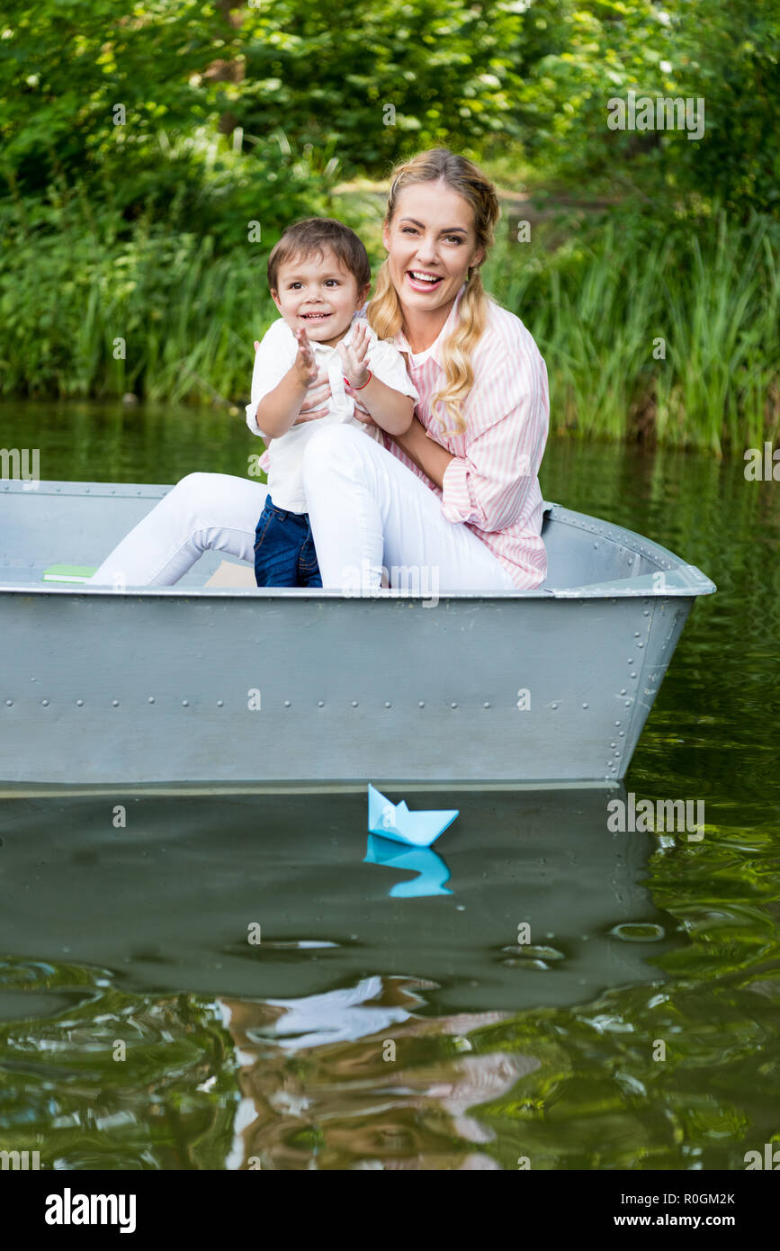 Felice madre con figlio equitazione barca sul lago in posizione di stazionamento e battendo le mani Foto Stock