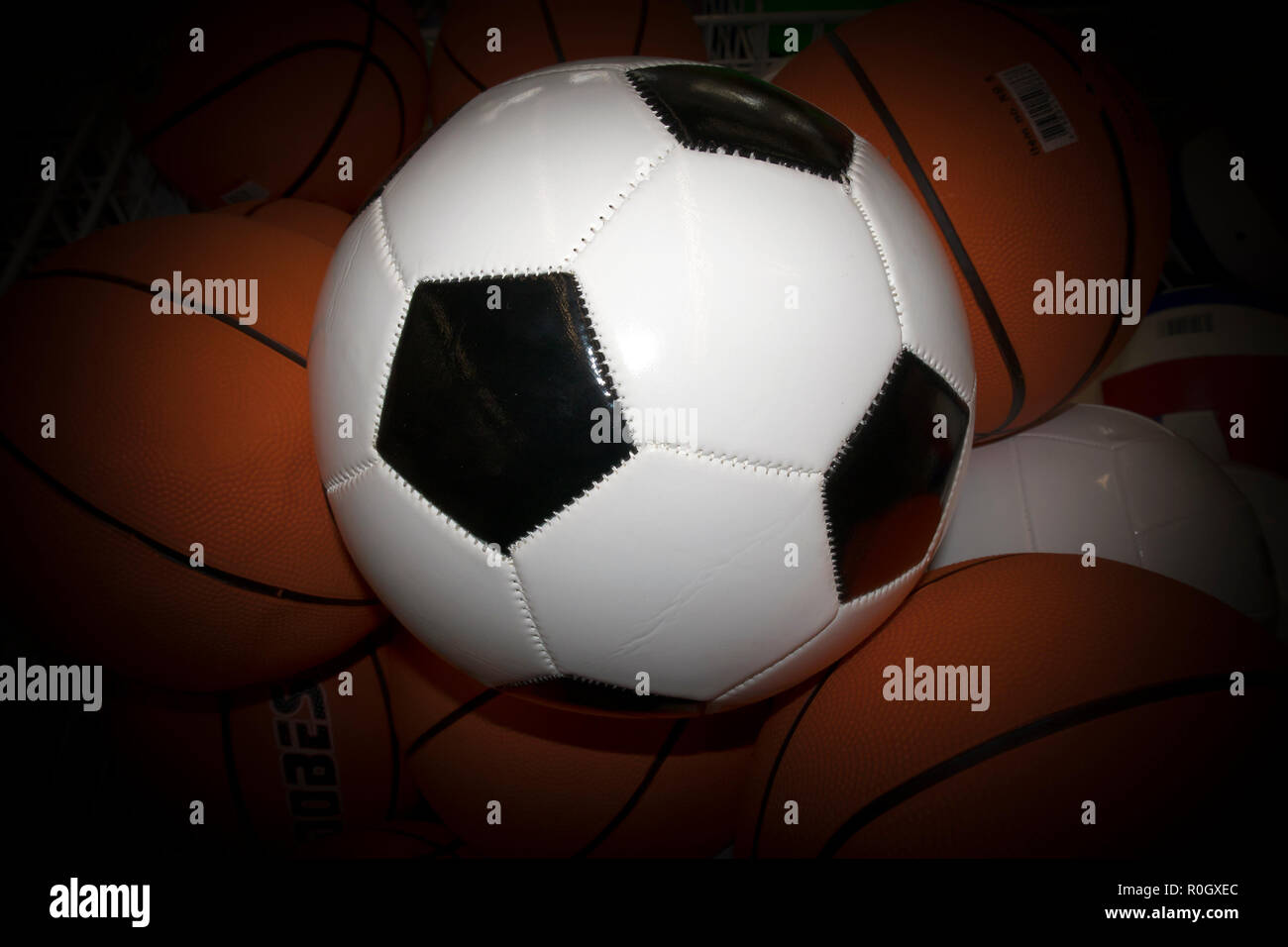 Bianco sfera di calcio con gli esagoni neri contro le sfere di colore arancione con bollino oscurato Foto Stock