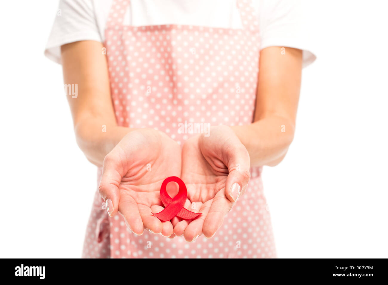 Immagine ritagliata della massaia in grembiule rosa azienda nastro rosso isolato su bianco, giornata mondiale dell aids concept Foto Stock