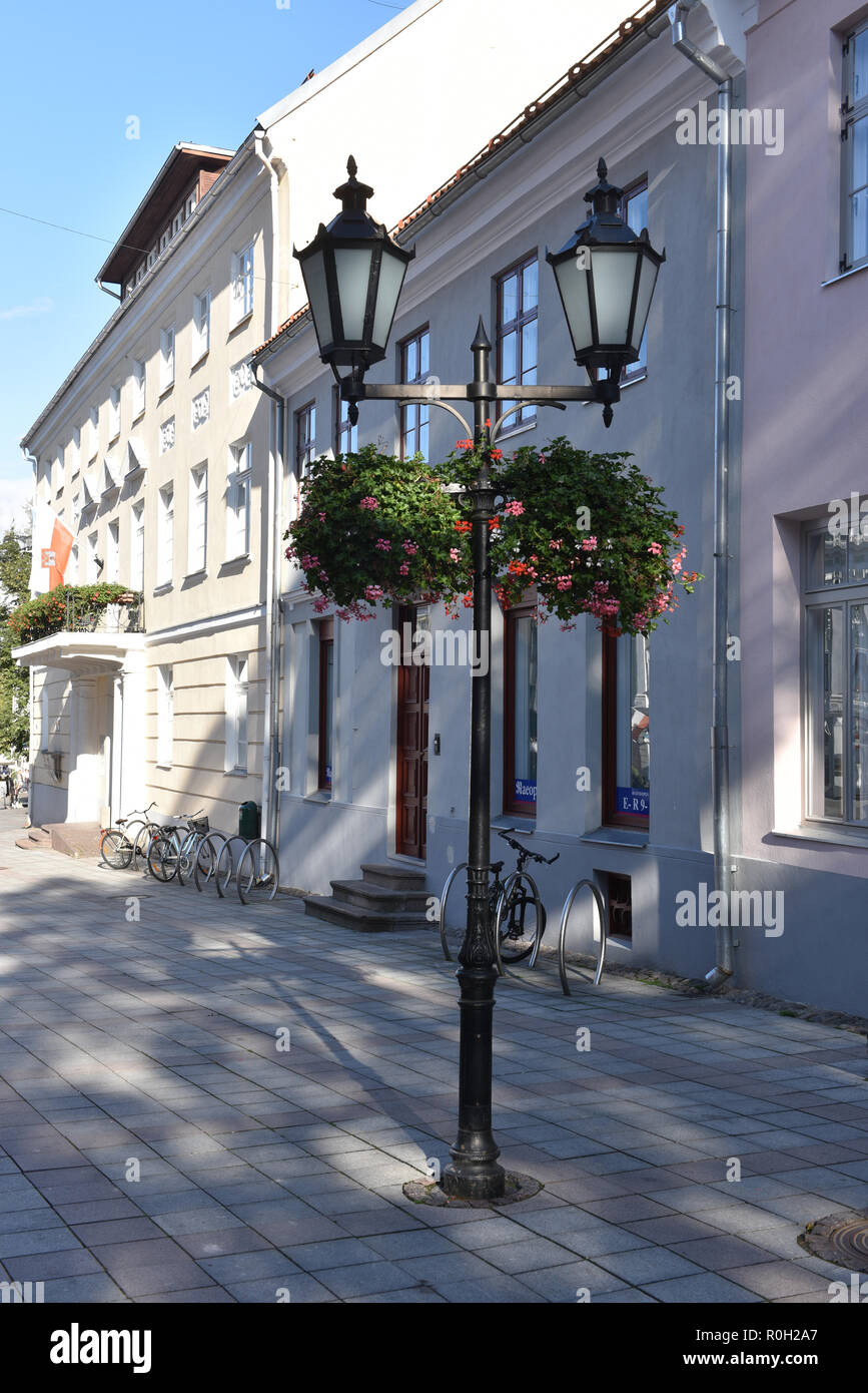 Old-style street lanterna con due lampade e vasi sospesi con fiori di colore rosso su strada Foto Stock