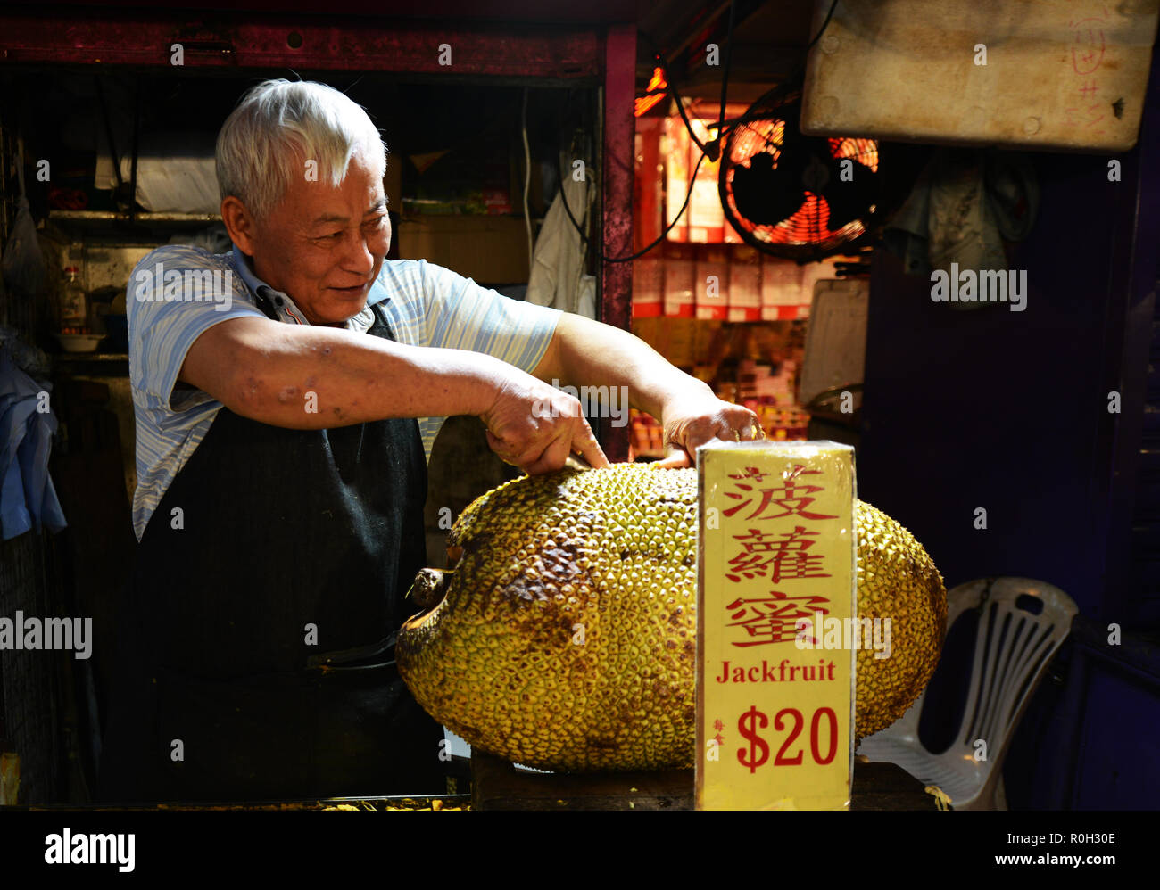 Il taglio di aprire un grande jackfruit presso il vivace mercato notturno in Mong Kok, Hong Kong. Foto Stock