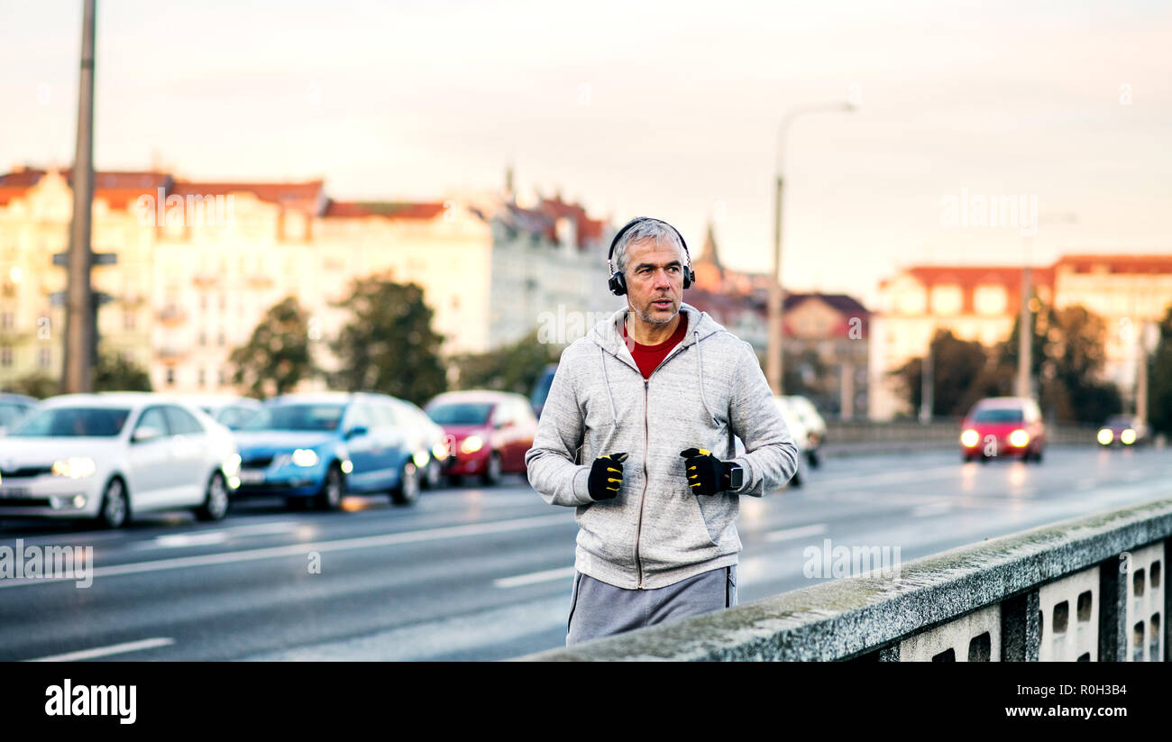 Maschio maturo runner con cuffie in esecuzione all'aperto sul ponte nella città di Praga. Foto Stock