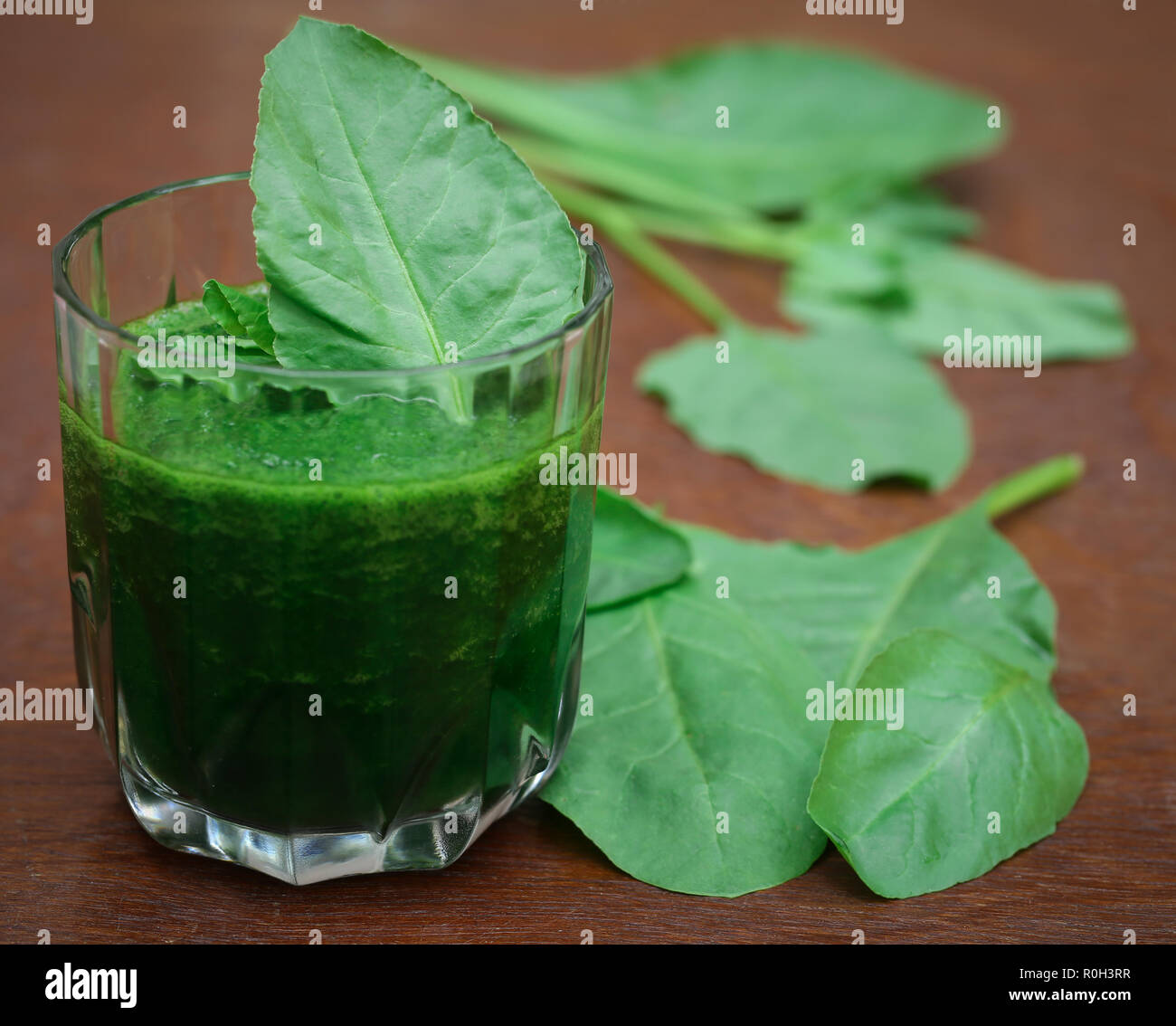 Purea di spinaci frullati in un bicchiere su una superficie di legno Foto Stock