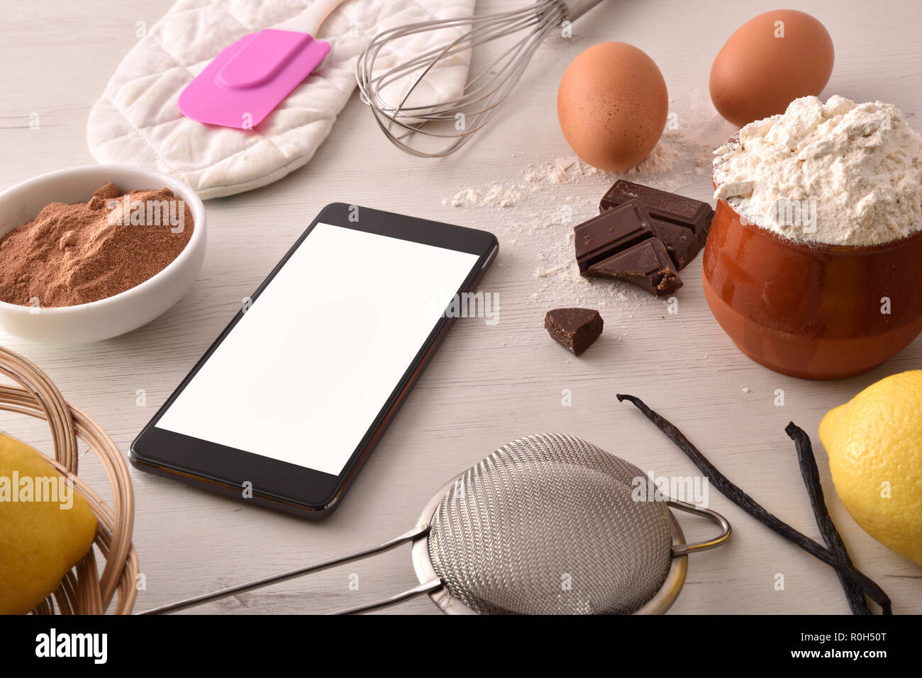 Gli ingredienti di pasticceria su una bianca tavolo in legno e mobili. Concetto di ricette nel libro digitale. Composizione orizzontale. Vista in elevazione Foto Stock