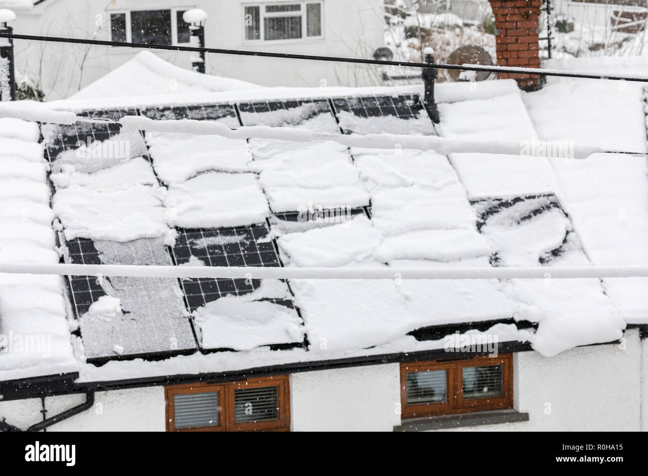I pannelli solari con neve lo scorrimento del coperchio off, Llanfoist, Wales, Regno Unito Foto Stock