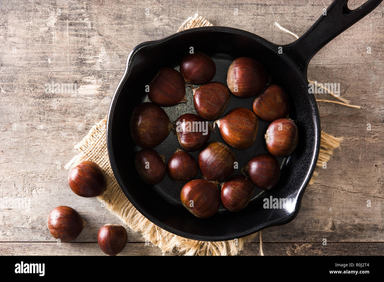 Le castagne in padella di ferro sul tavolo di legno. Vista superiore Foto Stock