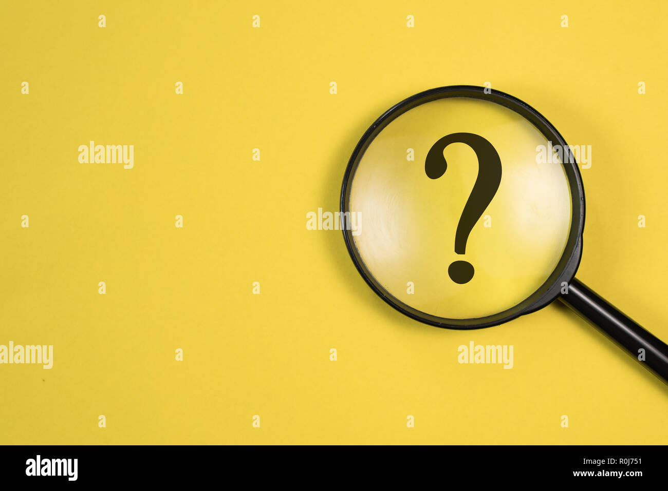 Lente di ingrandimento con il punto interrogativo nel fuoco su sfondo giallo. concetto di ricerca e ricerca. Foto Stock