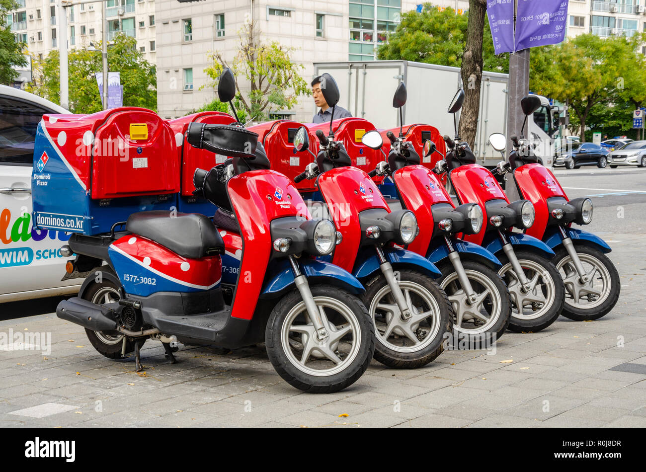 Il rosso e il blu dei Dominos consegna scooter ciclomotore parcheggiato ordinatamente in una linea su un pavimento in Seoul, Corea del Sud. Foto Stock