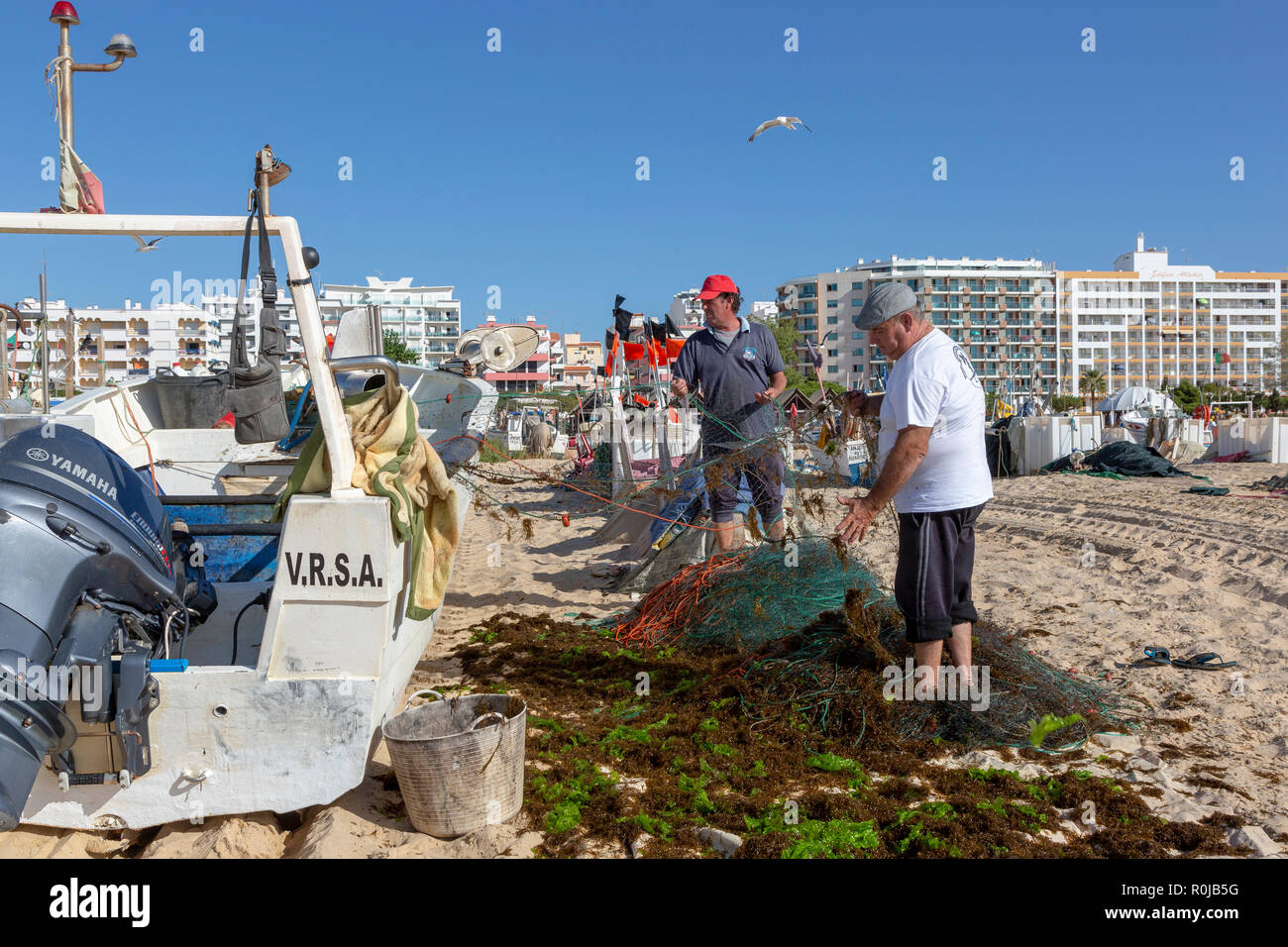 Pulizia dei pescatori e reimpostare le loro reti da pesca dopo giorni di pesca nel Mediterraneo, Monte Gordo beach, Algarve, PORTOGALLO Foto Stock