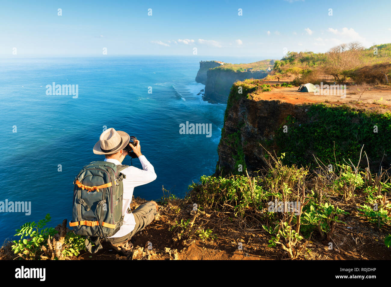 Fotografo in viaggio con fotocamera e foto zaino LovePro su top mountain cliff in background scenic natura paesaggio isola tropicale Foto Stock