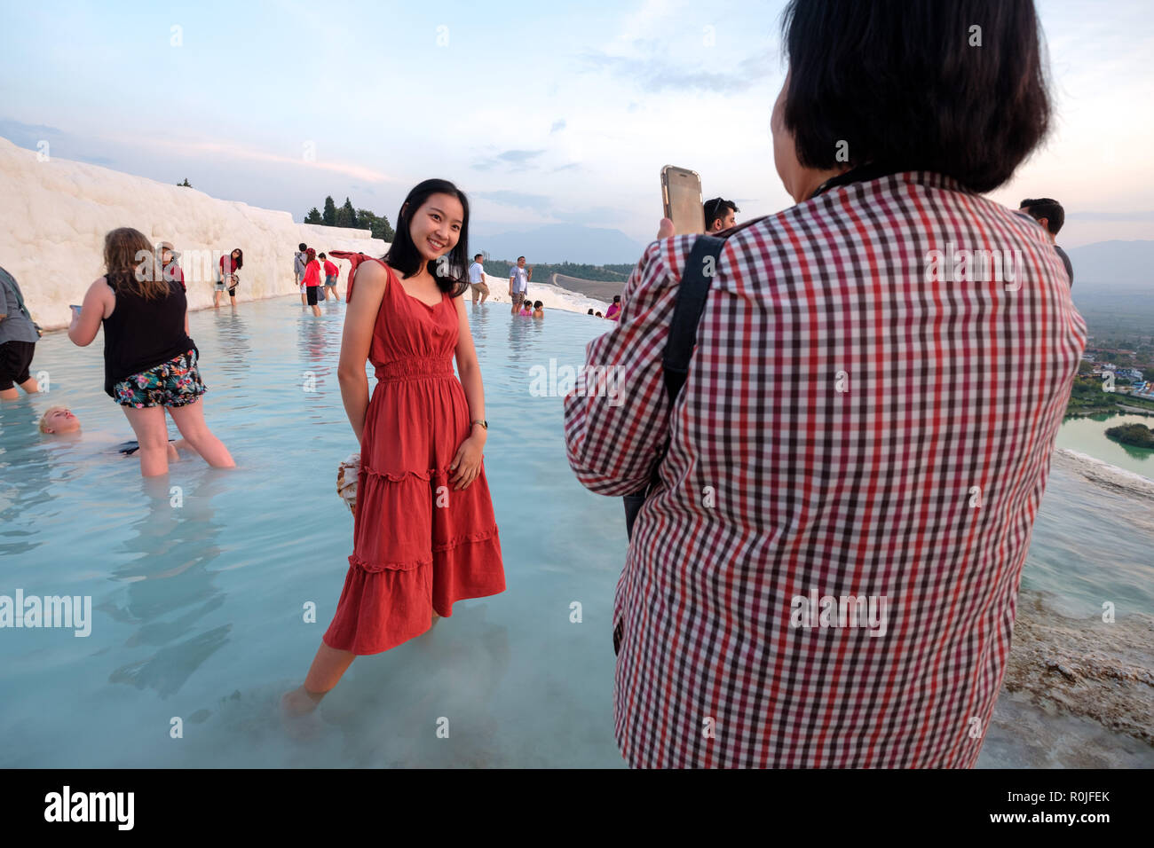 Giovane donna che indossa un abito rosso mentre avente la sua foto scattata a Pamukkale castello di cotone di travertino Piscine minerali, Antalya, Turchia Foto Stock
