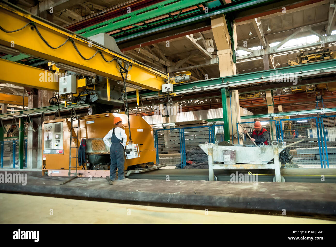 Tyumen, Russia - Agosto 13, 2013: creazione di blocco dipartimento al materiale di costruzione fabbrica ZHBI-5. Lavoratori di far funzionare la macchina per il riempimento di calcestruzzo plat Foto Stock