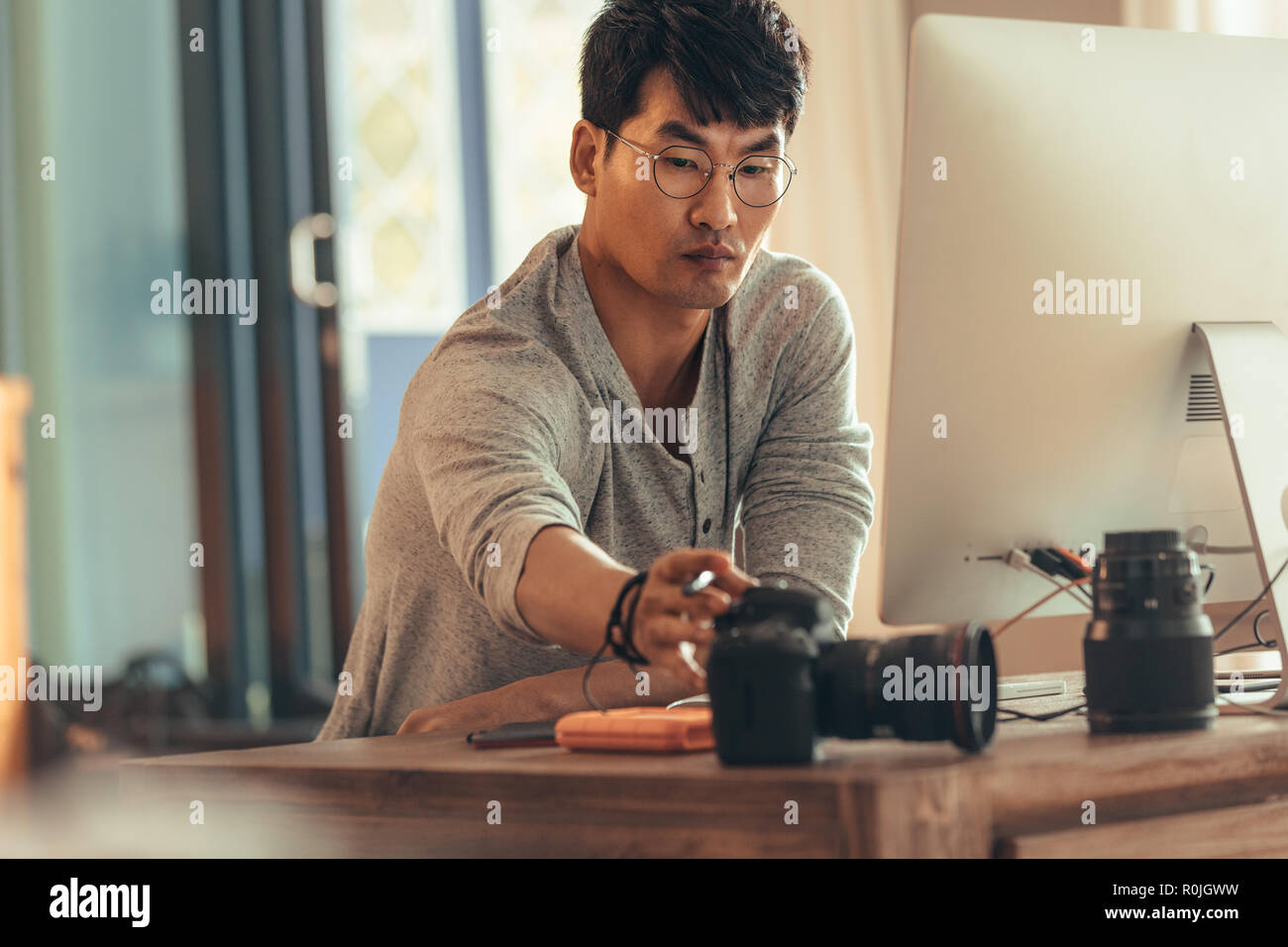 Fotografo di accendere la telecamera per trasferire le foto sul suo computer dopo lo scatto. Fotografo facendo post produzione sulle foto dopo photosho Foto Stock
