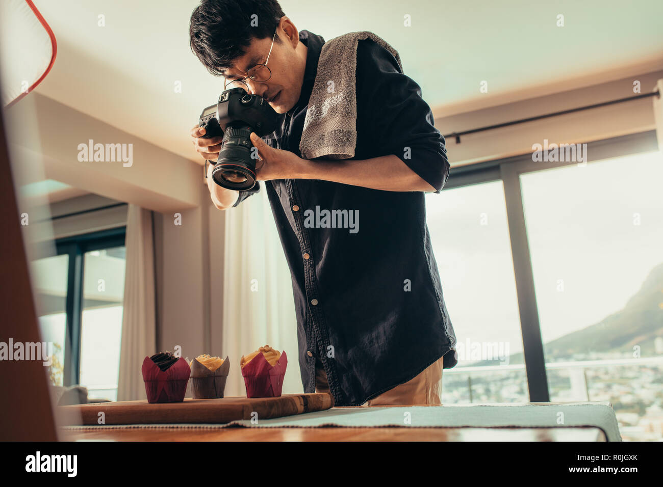 Professional cibo fotografo fotografare le tortine su tavola con fotocamera reflex digitale. Fotografo maschio a scattare foto di cibo dolce. Foto Stock