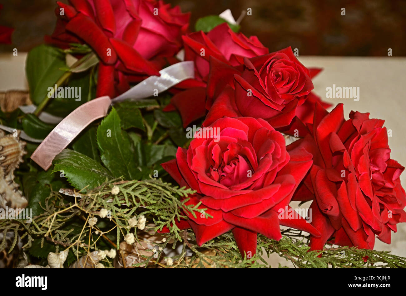 Bouquet di rose rosse con rametti di eucalipto, conchiglie, nastro di raso Foto Stock