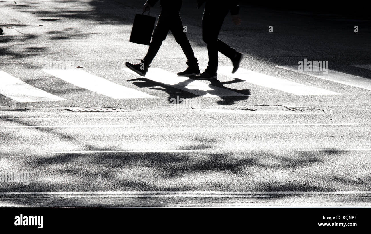 Sfocata ombra silhouette di due pedoni che attraversano una strada di città, in bianco e nero Foto Stock