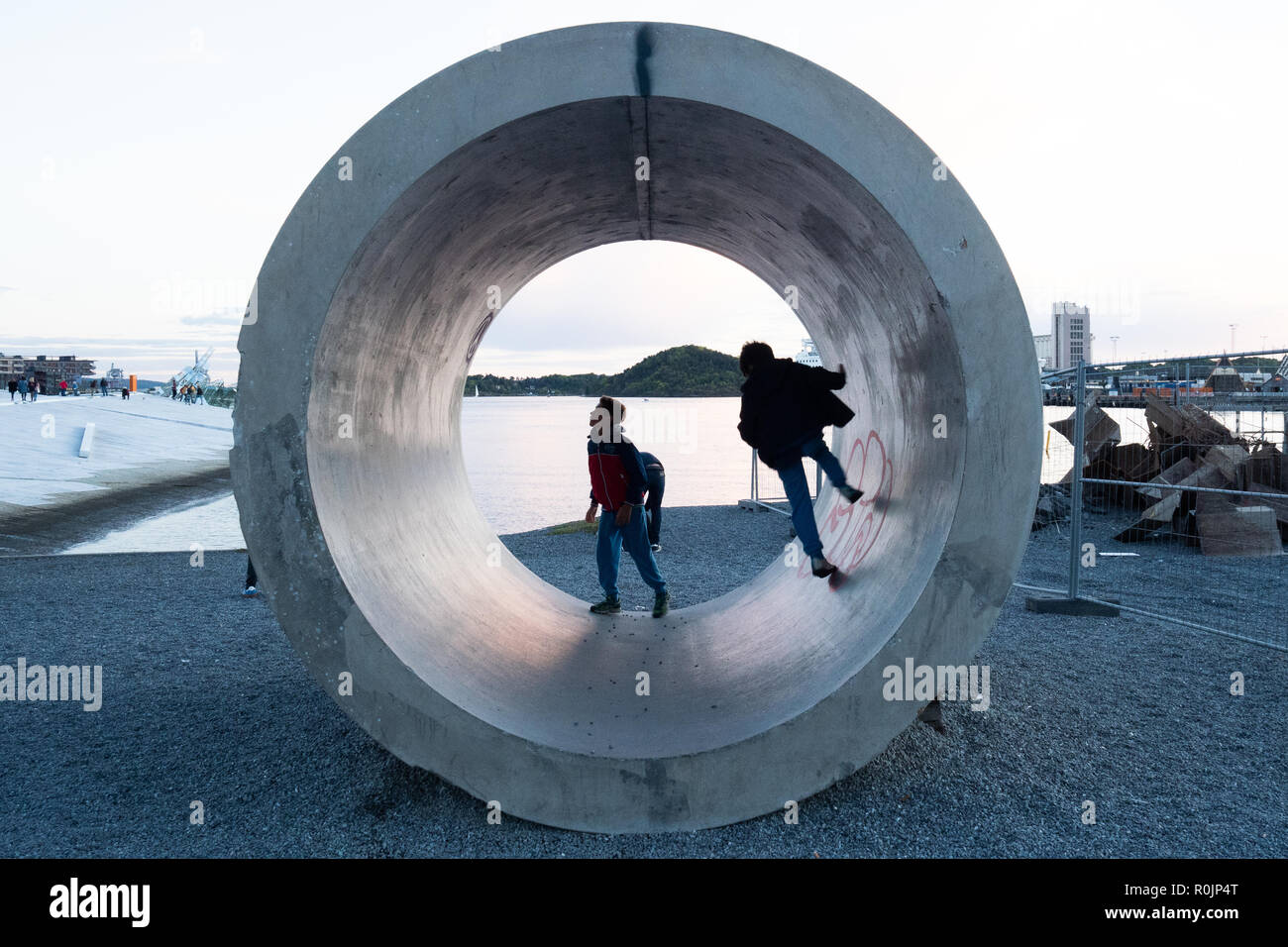 I bambini giocando in un tubo di calcestruzzo di fronte alla Opera House di Oslo, Norvegia Foto Stock