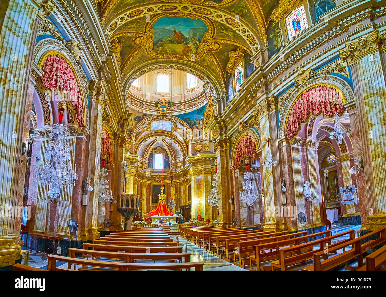 NADUR, Malta - 15 giugno 2018: la splendida sala da preghiera di san Pietro e Paolo Basilica con colonne in pietra e ornato di lampadari di vetro, il 15 giugno a Na Foto Stock