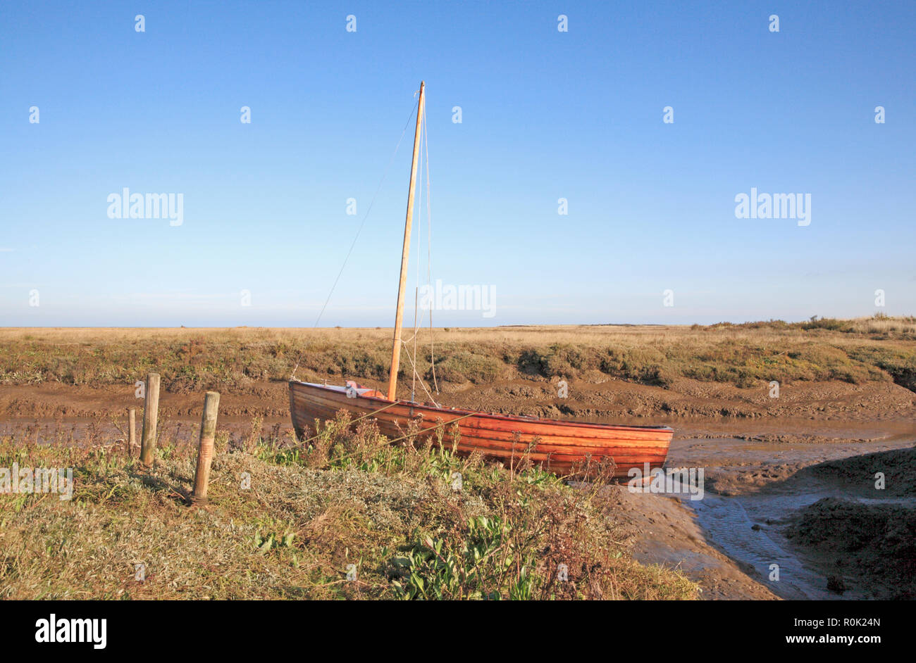 Una barca a vela dinghy legato da un torrente di marea in Salt Marsh sulla Costa North Norfolk a Thornham, Norfolk, Inghilterra, Regno Unito, Europa. Foto Stock