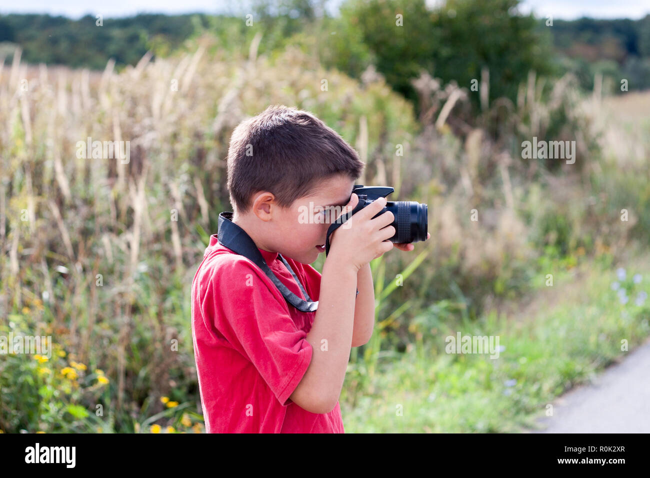 Ritratto di un giovane ragazzo in possesso di una moderna fotocamera digitale Foto Stock