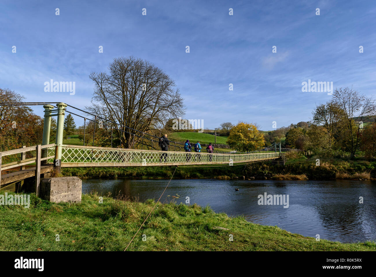 Walkers sul Dales modo attraversando la sospensione Hebden Bridge sul fiume Wharfe Foto Stock