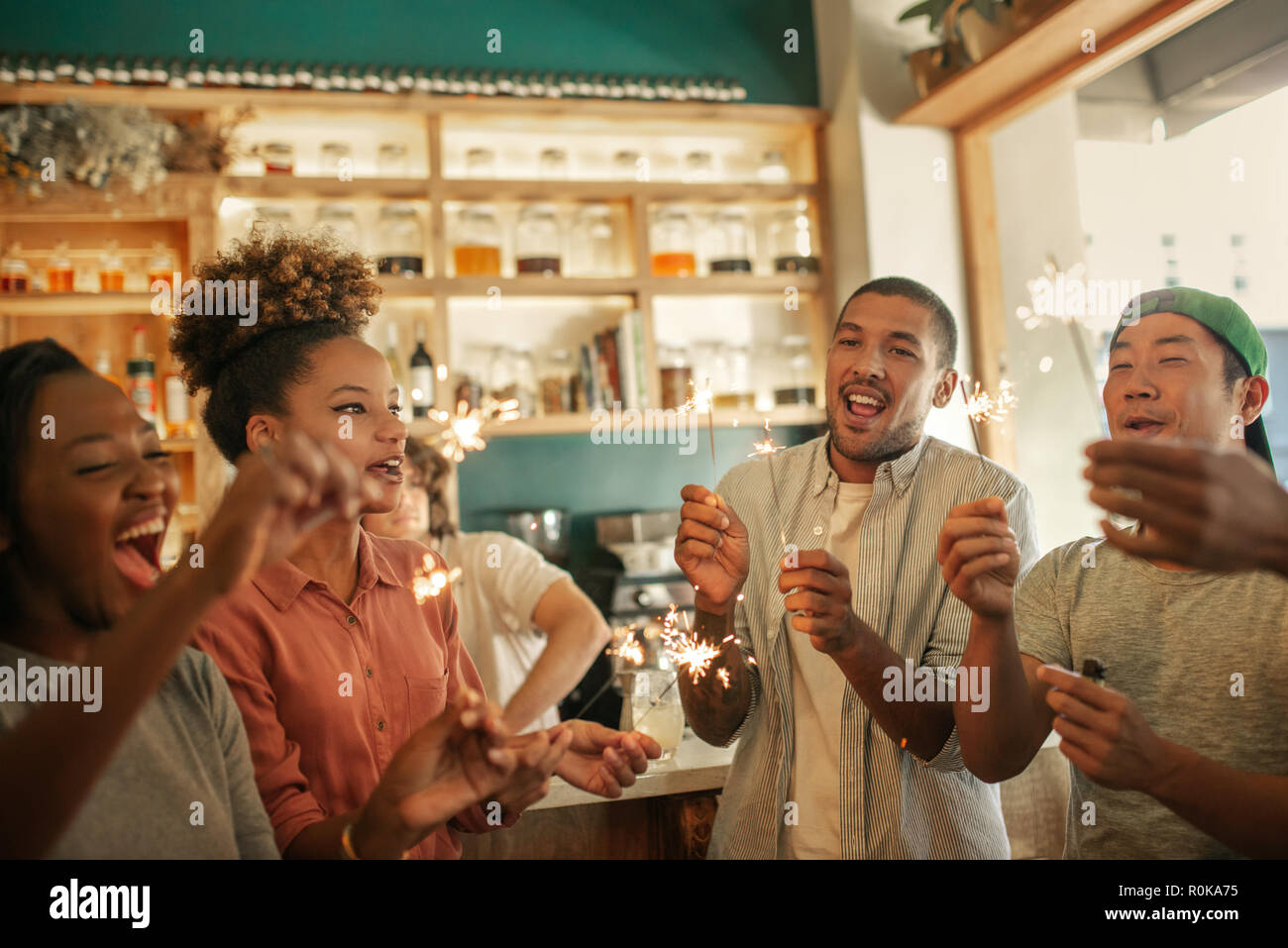 Ridendo gruppo di amici celebrando con botti in un bar Foto Stock