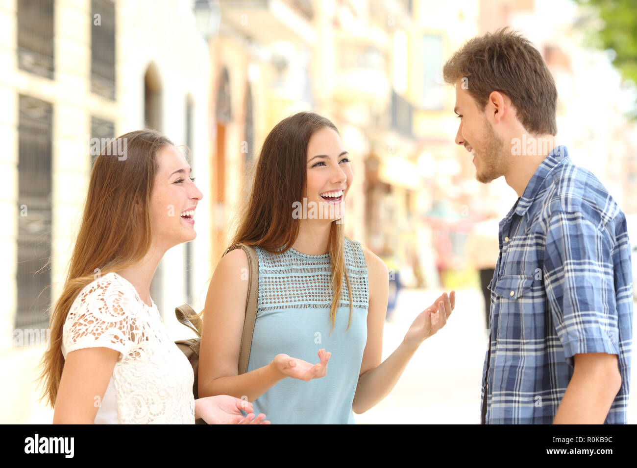 Tre amici smiley a parlare e ridere in strada Foto Stock