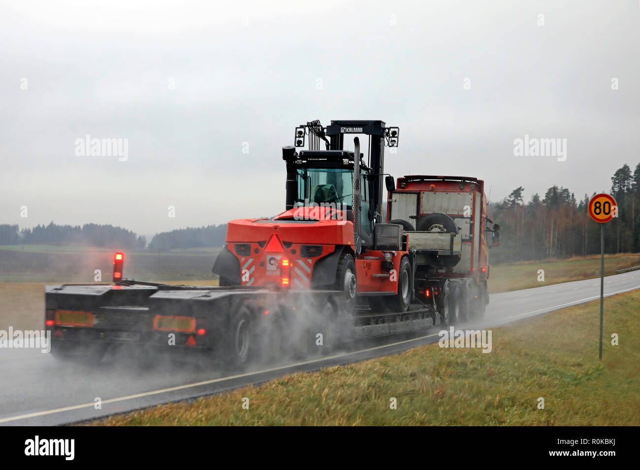 Salo, Finlandia - 2 Novembre 2018: Scania semi rimorchio di Kosken Autokeskus cale grandi KALMAR carrello elevatore su bagnato autostrada in un giorno di pioggia, in vista posteriore Foto Stock