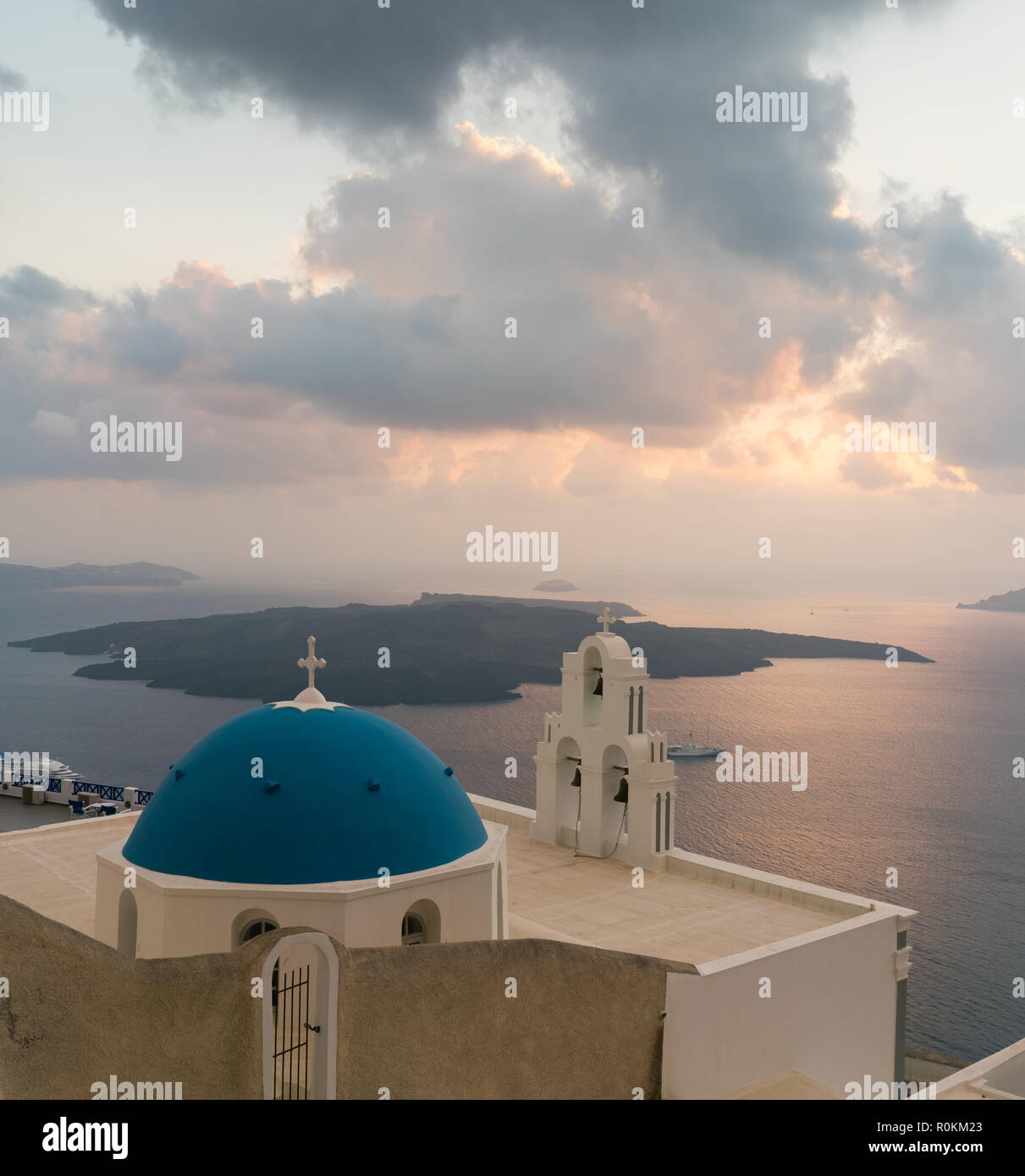 Tramonto sul mare egeo con vista alla Vergine Maria la Chiesa cattolica tre campane di Fira, Santorini. Foto Stock