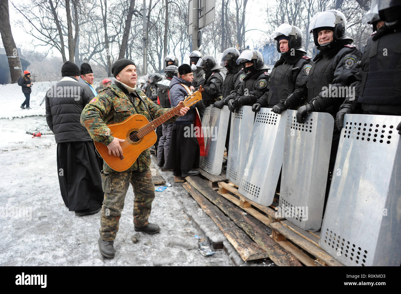 28 gennaio 2014 - Kiev, Ucraina: un manifestante suona la chitarra nella parte anteriore della polizia antisommossa custodendo il parlamento come un teso standoff continua tra il Maidan manifestanti e forze di polizia. Nazioni Unite manifestant joue de la guitare pour detendre l'atmosfera devant une rangee de polciiers anti-emeute pres de la place maidaïen a Kiev. *** La Francia / NESSUNA VENDITA A MEDIA FRANCESI *** Foto Stock