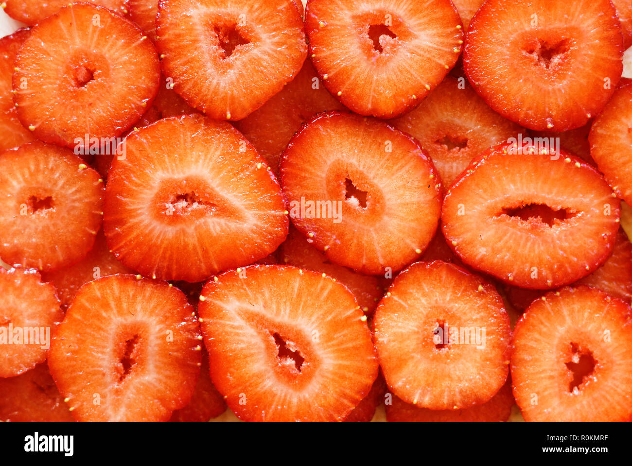 Fragola. Fresche succose fette di maturi frutti esotici. Natura sfondo rosso Foto Stock