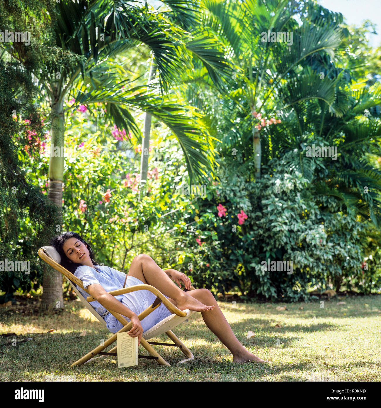 Giovane donna napping in sedia a sdraio, giardino tropicale, Guadalupa, French West Indies, Foto Stock