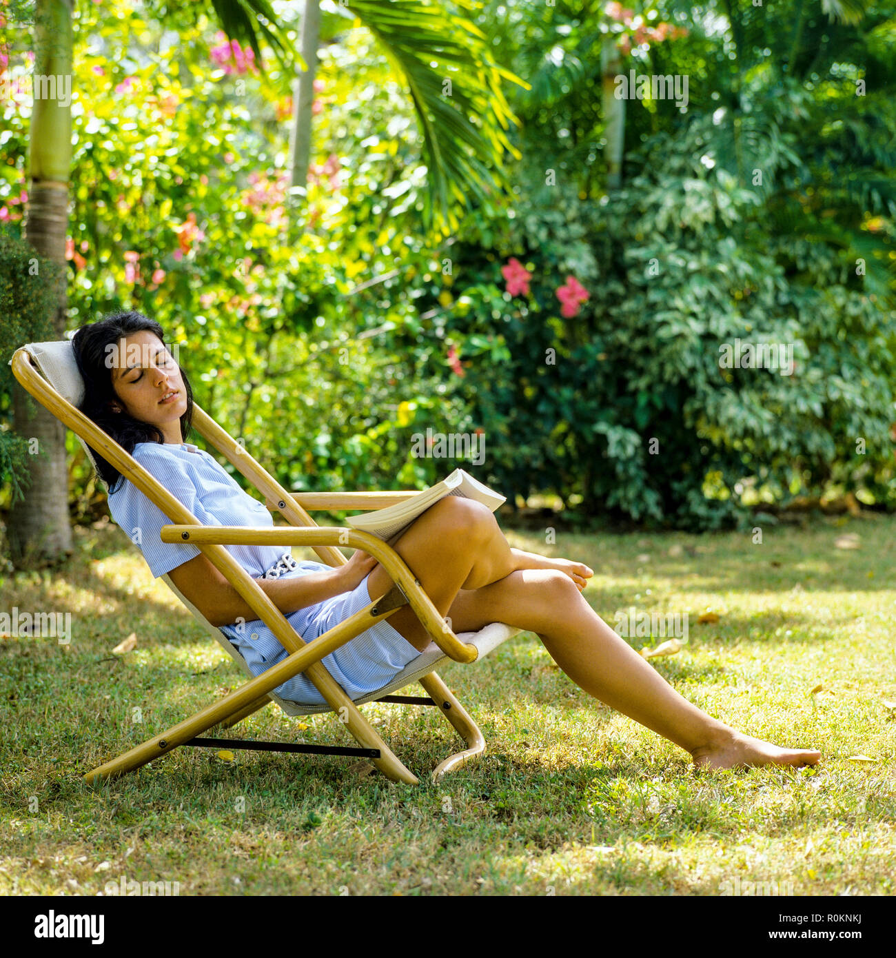 Giovane donna napping in sedia a sdraio, giardino tropicale, Guadalupa, French West Indies, Foto Stock