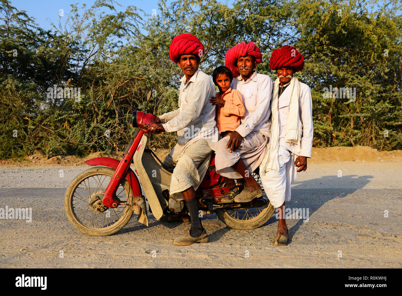 Quattro uomini da tre generazioni in sella insieme su un motociclo, Rajasthan, India Foto Stock