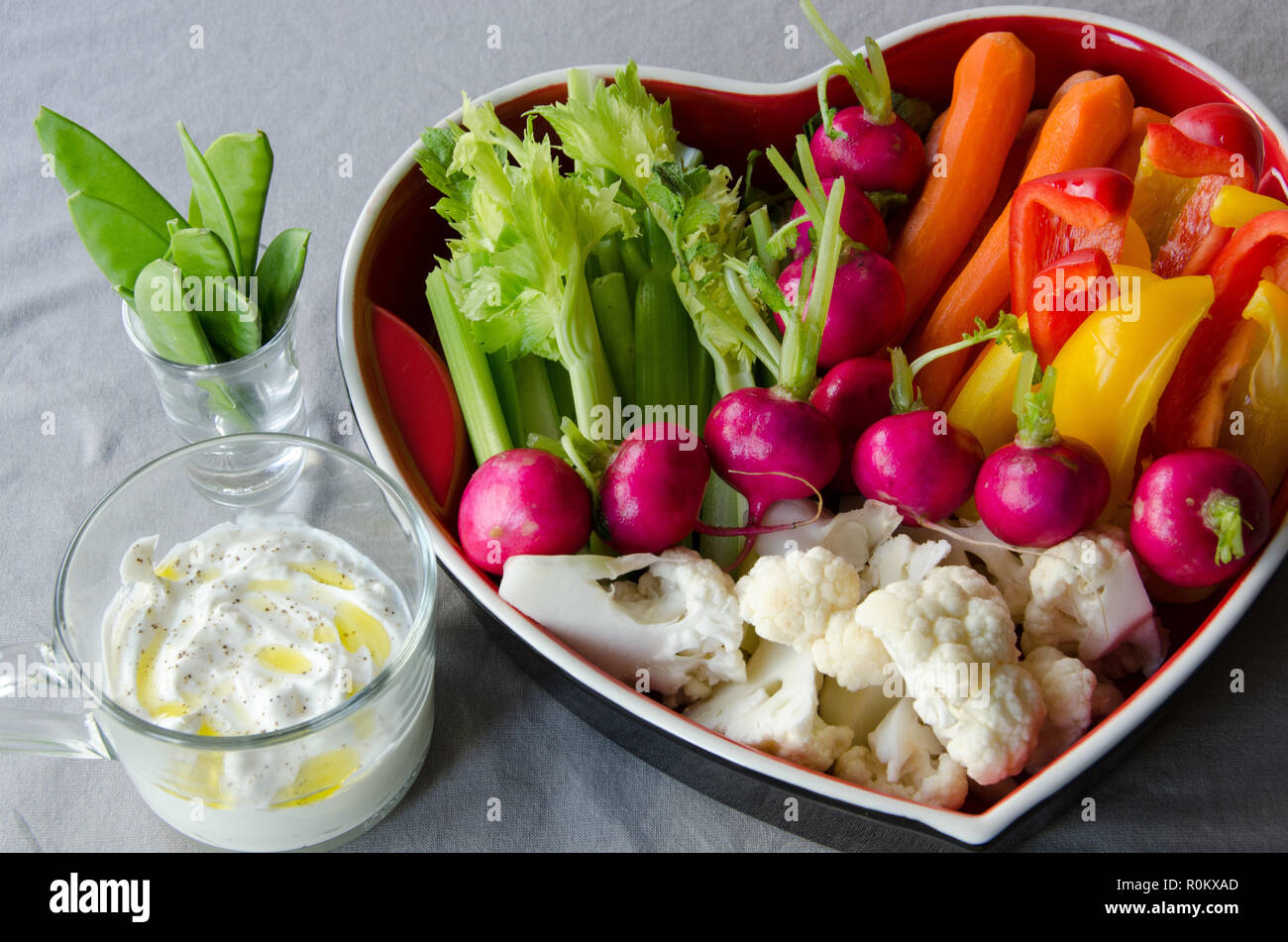 Verdure in un vassoio heartshaped pronto a mangiare su sfondo chiaro. Foto Stock