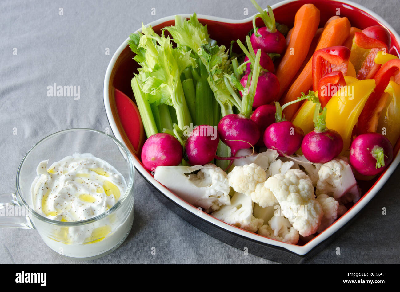 Verdure in un vassoio heartshaped pronto a mangiare su sfondo chiaro. Foto Stock