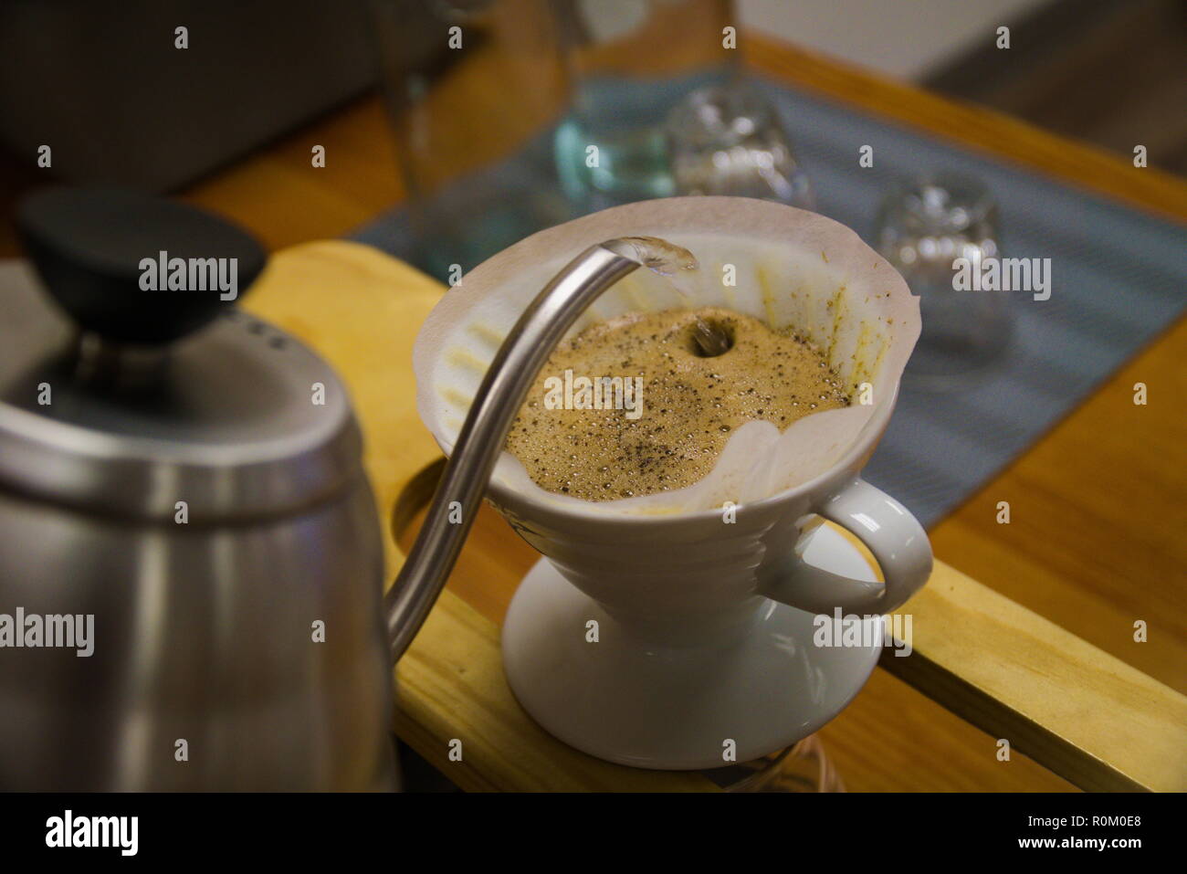 L'acqua da un bollitore è versata in un filtro da caffè seduti in una tazza. Il barista è messa a versare il caffè. Foto Stock