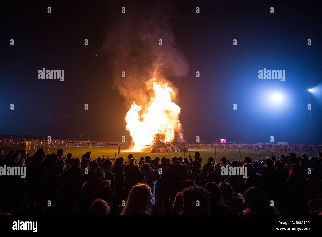 La gente si vede guardando la fiamma enorme durante la raccolta per celebrare il falò e fuochi d'artificio in Roundhay Park, Leeds. Foto Stock