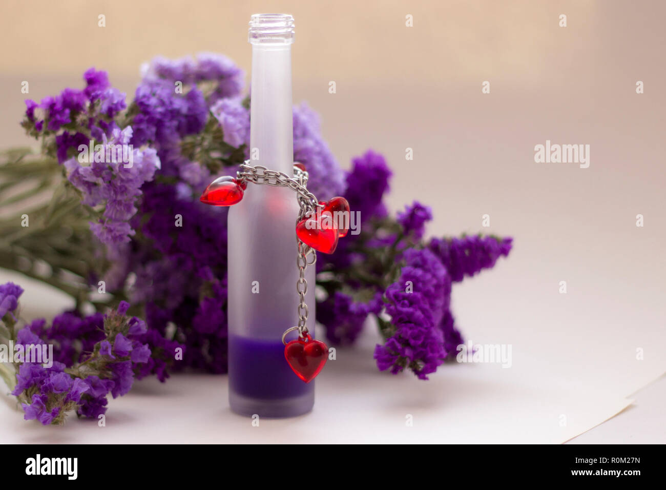 Olio essenziale in matt bottiglia sui fiori viola la sfocatura dello sfondo. Foto Stock