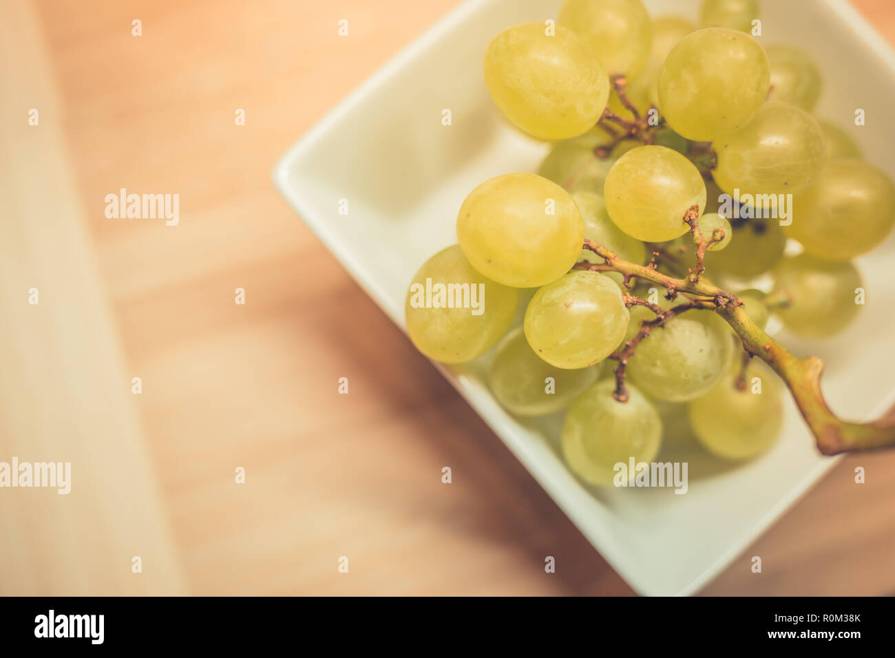 Grappolo di uva verde nel cestello, frutti dell'autunno, un simbolo di abbondanza su legno rustico sfondo con copia spazio, vista dall'alto, close-up. Foto Stock
