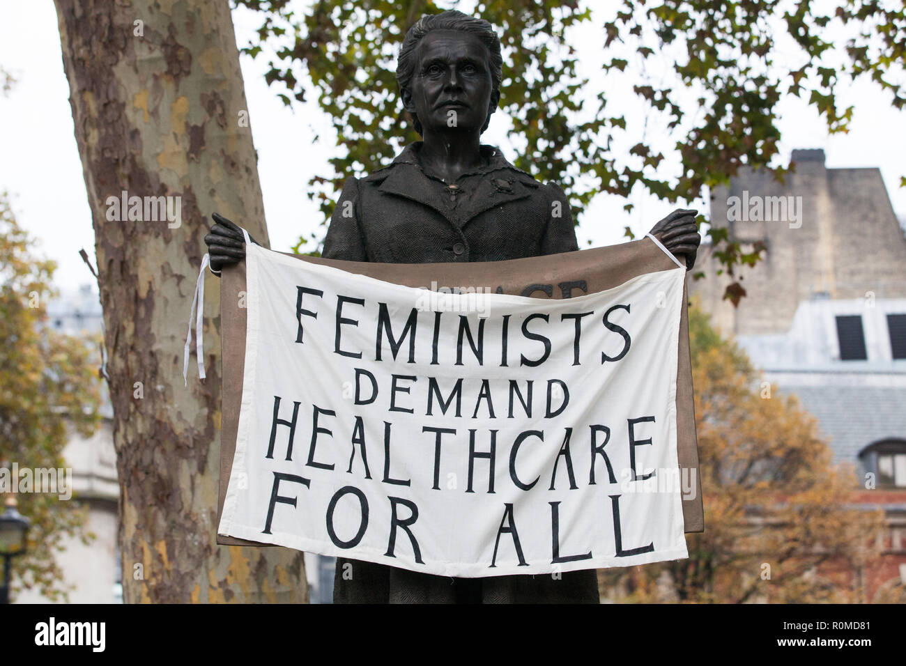 Londra, Regno Unito. 6 Novembre, 2018. Gli attivisti da rimonta femminista vestito come suffragettes cambiare il segno sul nuovo Millicent Fawcett statua in piazza del Parlamento da 'Coraggio chiamate al coraggio ovunque' a 'femministe richiesta assistenza sanitaria per tutti" in segno di protesta contro la NHS oneri per i migranti. Sotto il nuovo NHS il sistema di ricarica, i migranti non sono considerati "stabilmente residente" nel Regno Unito vengono caricati fino a € 7000 per la gravidanza cura e £1300 per un aborto in un ospedale di NHS. Credito: Mark Kerrison/Alamy Live News Foto Stock