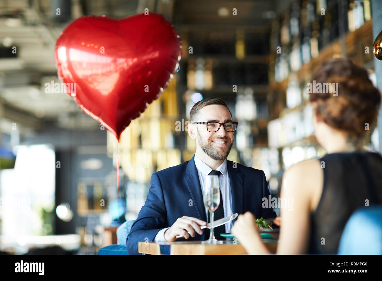 Felice giovane uomo guardando la sua ragazza durante il pranzo in ristorante a san valentino Foto Stock